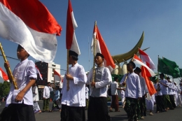 Peserta membawa bendera merah putih saat mengikuti Kirab Hari Santri Nasional di Perempatan Kartonyono, Ngawi, Jawa Timur, Senin (21/10/2019).| ANTARA FOTO/ARI BOWO SUCIPTO