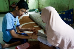 Fitriani (45) mendampingi putranya, Arief Fadillah belajar di rumah (Sumber: KOMPAS/SUCIPTO)