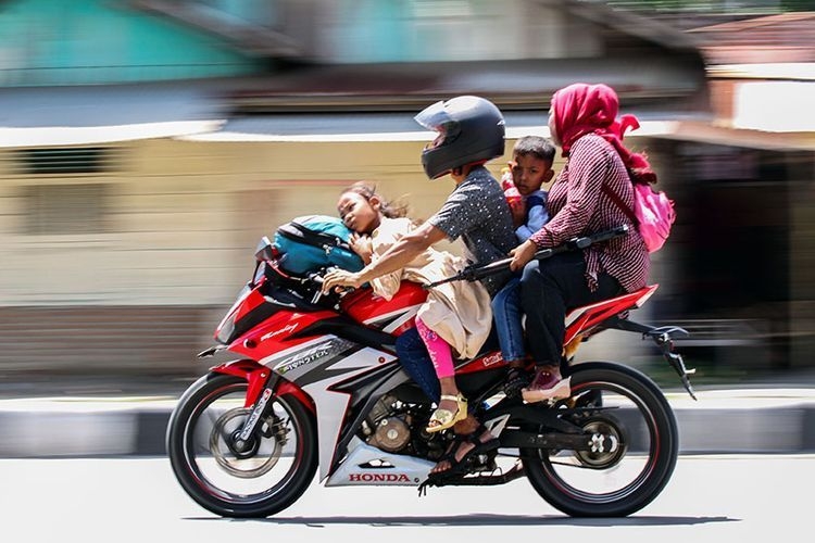 Ilustrasi pengendara sepeda motor membonceng keluarganya yang tak menggunakan helm. Sumber: Antara Foto/Rahmad via Kompas.com