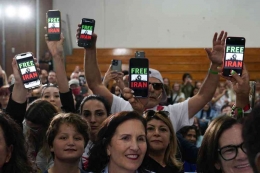Orang-orang mengangkat telepon yang menampilkan kata-kata 'Bebaskan Iran' ketika Presiden Joe Biden berbicara pada acara kampanye Kamis, 3 November 2022, di San Diego, California. (Foto AP/Patrick Semansky)
