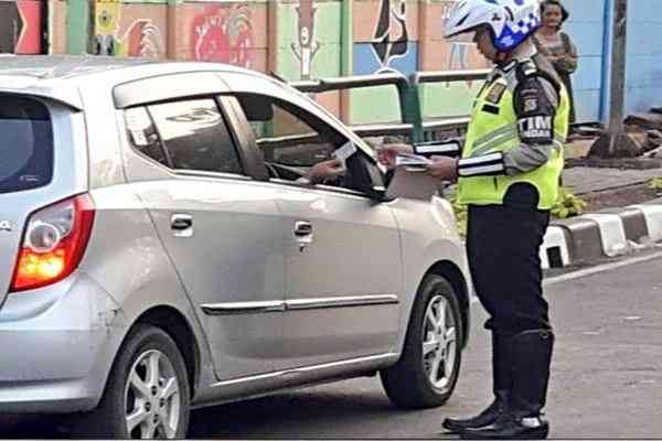 Ilustrasi polisi menilang pelanggar lalu-lintas (Foto: Twitter @tmcpoldametro caption via bisnis.com)