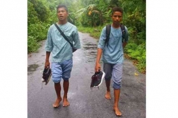Siswa SMA Negeri 1 Nusalaut, Kab. Maluku Tengah, Maluku, berjalan kaki di bawah gerimis hujan dari sekolah ke rumah.(Kompas/Fransiskus Pati Herin) 
