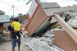 Seorang warga melintas di depan rumah yang ambruk akibat gempa di Cibulakan, Cugenang, Cianjur, Rabu (23/11/2022). | Kompas/Firman Taufiqurrahman