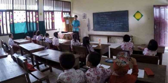 Seorang guru sedang mengajar di kelas (Sumber: Kompas.com)