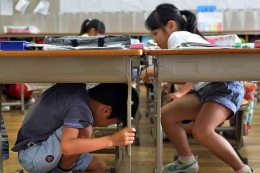 Anak-anak sekolah di Jepang diajari simulasi grmpa bumi. | FOTO AFP / Yoshikazu TSUNO (YOSHIKAZU TSUNO) via: kompas.com
