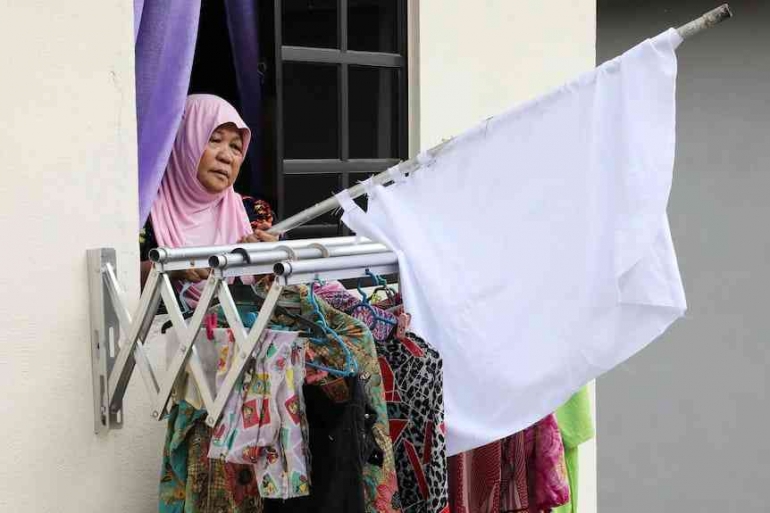 Seorang perempuan Malaysia mengibarkan bendera putih minta bantuan. (Reuters: Lim Huey Teng) via ABC.net.id
