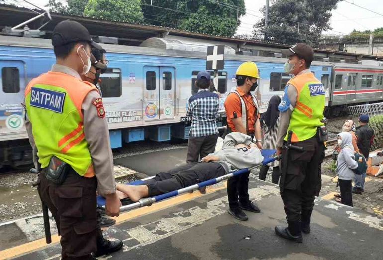 Petugas Stasiun Karet sedang menandu penumpang yang pingsan di KRL Commuter Line