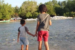 Seorang anak laki-laki memegangi tangan kakaknya karena takut ketika air laut sedang surut  di Pantai Walakeri, Sumba Timur, NTT (Foto:Lex) 