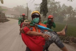 Seorang petugas terlihat tengah mengevakuasi warga saat erupsi Gunung Semeru, Minggu 4/12/2022. (Dok BNPB via Kompas.com)