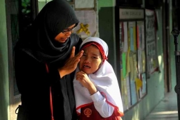 Ilustrasi seorang guru yang sedang menenangkan peserta didiknya yang menangis (sumber: edukasi.kompas.com)