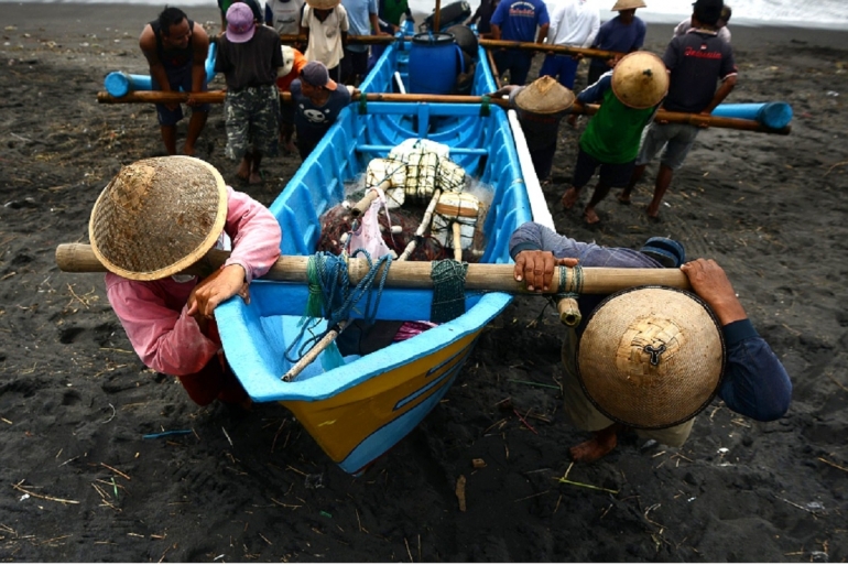 Nelayan membantu menepikan kapal yang baru saja digunakan untuk mencari ikan di Pantai Depok, Bantul, DI Yogyakarta, Rabu (14/1/2021). Foto: Kompas/Ferganata Indra Riatmoko