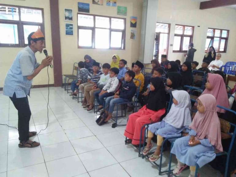 Anak-anak serius mendengarkan Kak Dimas mendongeng. Gambar Dokat