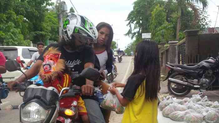 Seorang anak sedang menawarkan sekantong bunga rampai kepada pengendara sepeda motor di Kota Kupang (dok foto: tribunnews.com)