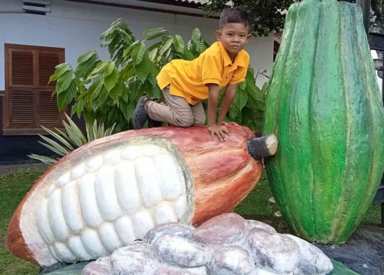 Berpose di atas buah coklat raksasa di Doesoen Kakao-Banyuwangi. Sumber: Dokpri