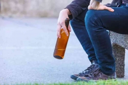 Man depressed with wine bottle sitting on bench outdoor (by Voyagerix @ everypixel.com)