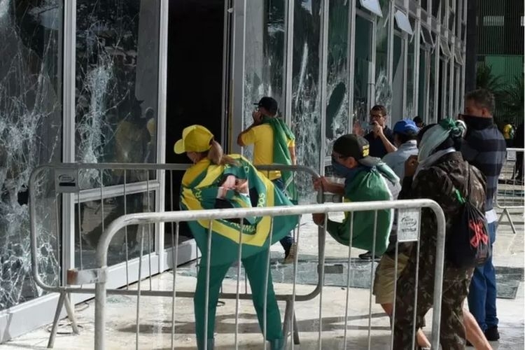 Sejumlah demonstran pendukung mantan Presiden Jair Bolsonaro memecahkan kaca Mahkamah Agung dalam serbuan di ibu kota Brasilia, 8 Januari 2023.(AFP/GETTY via BBC INDONESIA/kompas.com)