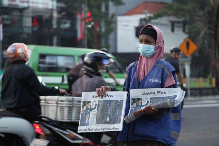 Luluk Istiana (60),menawarkan koran kepada pengguna jalan yang lewat untuk membeli koran nya. Yang berlokasi di Jalan Ahmad Yani gayungan, Surabaya./D