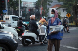Luluk Istiana(60) Menawarkan koran kepada pengguna jalan yang menunggu lampu merah di jalan Ahmad Yani gayungan, Surabaya untuk membeli korannya.