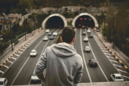 Man in Grey Hoodie Standing on Bridge over the Expressway (pexel.com) 