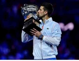Novak Djokovic mencium Trophy Australian Open 2023 ia meraih Juara untuk kesepuluh kalinya (foto: AFP via Getty Images/Manan Vatsyana))