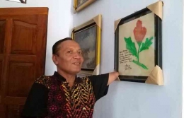 Agus kala menunjukkan salah satu lukisannya yang mendapat tanda tangan alm. Tien Soeharto | Kompas.com