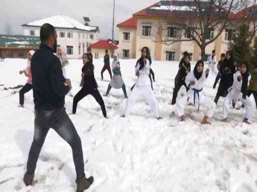 Seorang pelatih sedang melatih  para siswi yang tak pakai sepatu di atas salju dari sebuah akademi seni bela diri Jammu dan Kashmir. | Sumber: ANI