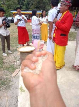 Gora-gora tongkon (baju merah) sedang memandu rumpun keluarga untuk mengambil beras di depan tongkonan. Sumber foto: Dok. Pribadi.
