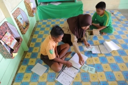 Warsiah, Kepala SDN 013 Desa Bulu Perindu, Kecamatan Tanjung Selor, Kalimantan Utara memberikan bimbingan membaca kepada siswa dengan metode kartu baca.(Dok. Inovasi Kaltara via kompas.com)