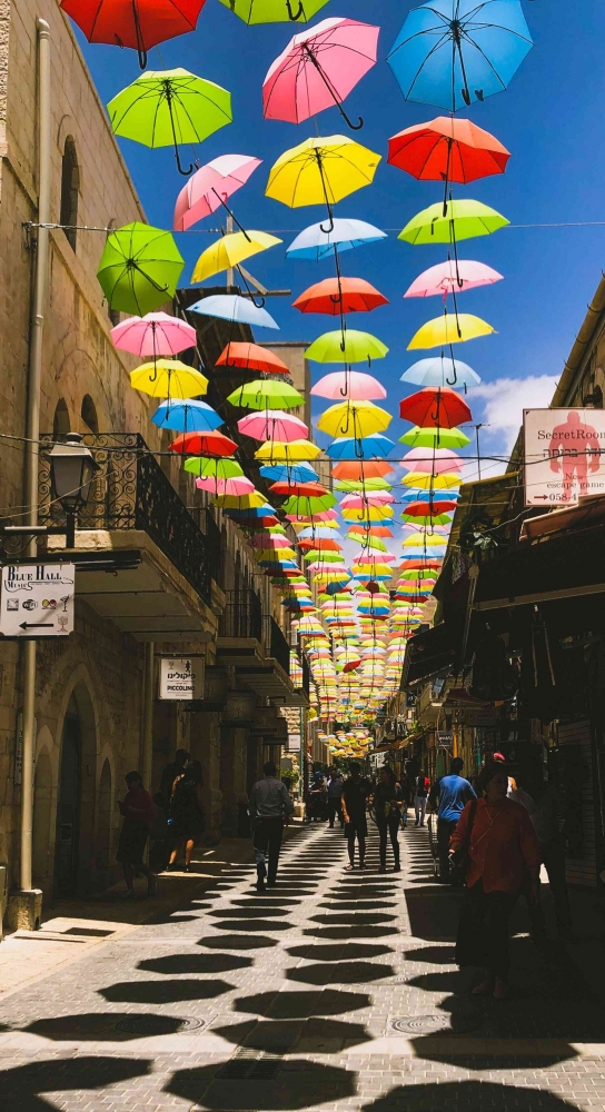 Ilustrasi: Sebuah jalan di Yerusalem yang dipenuhi dengan payung-payung beraneka warna. Sumber: Unsplash / Chana Gold