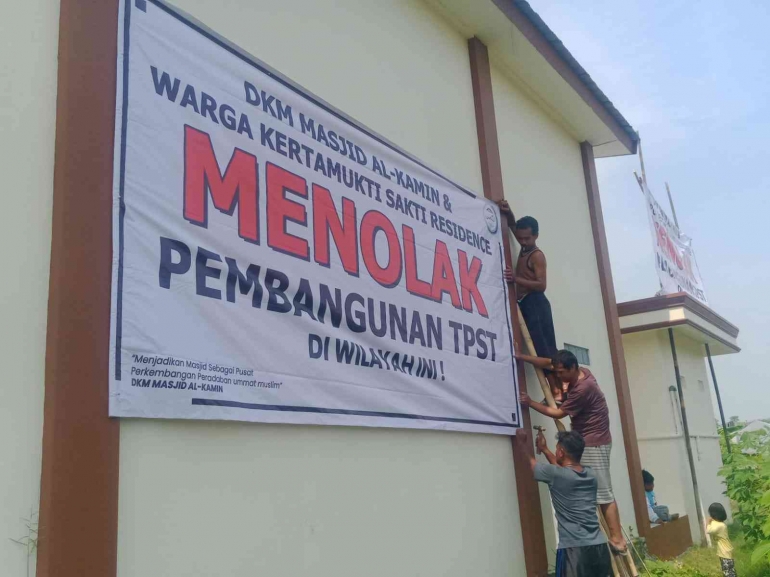 Foto warga sedang memasang spanduk penolakan TPST dibelakang masjid Al-Kamin - Dokpri