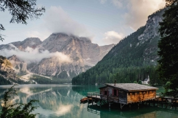 Ilustrasi: Sebuah rumah di daerah yang sangat tenang dengan danau dan pegunungan. Sumber: Unsplash / Luca Bravo