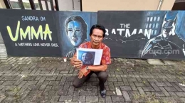 Parsan tengah melukis poster film yang akan diputar di Bioskop Rajawali Purwokerto, Rabu (23/3/2022). [Suara.com/Anang Firmansyah] 