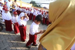 Ilustrasi: Siswa bersalaman dengan guru sebelum masuk kelas. (KOMPAS.com/ANDREAS LUKAS ALTOBELI)