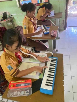 Siswa belajar alat musik pianika. (sumber: dokumentasi pribadi.)