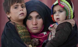 Seorang perempuan Afghanistan memeluk anak-anaknya saat ia menunggu konsultasi di luar sebuah klinik sementara di Herat. | AP