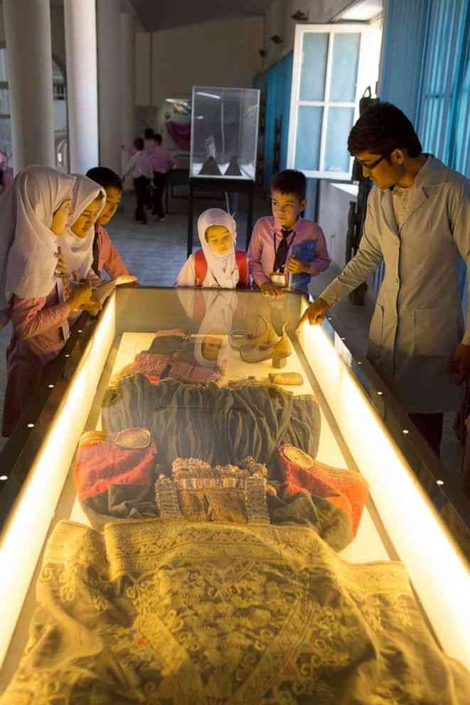 Anak-anak sekolah menatap salah satu pameran etnografi di Museum Nasional Afghanistan, yang memamerkan pakaian tradisional, perhiasan, dan kostum yang