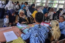 Antrean siswa dengan orangtua murid mengikuti seleksi Penerimaan Peserta Didik Baru (PPDB) di SMAN 2 Kota Tasikmalaya, Jawa Barat, Senin (17/6/2019).(ANTARA FOTO/ADENG BUSTOMI)