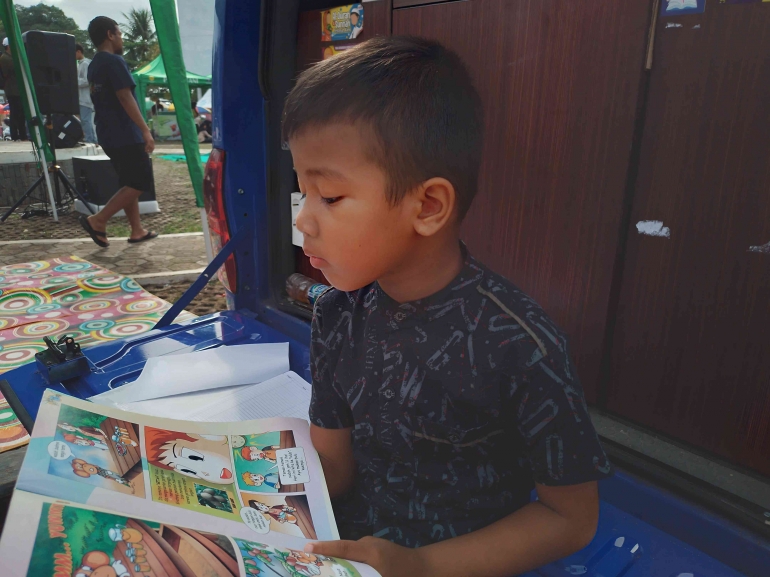 Seorang Anak Sedang Membaca Buku Di Mobil Perpustakaan Keliling/Foto: Agustian Deny Ardiansyah