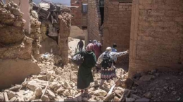 Warga berusaha melalui jalan yang tertimbun reruntuhan bangunan akibat gempa Maroko, Sabtu (9/9/2023) (Sumber: AP Photo via KOMPAS.com)