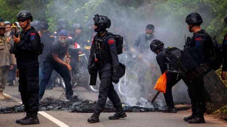 Ilustrasi. Aparat sedang membersihkan jalan setelah kerusuhan Rempang. Foto oleh Teguh Prihatna/ Antara via bbc.com
