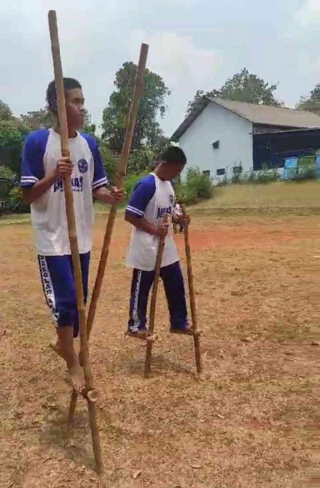 Pemain menaiki tongkat bambu dan berjalan menggunakan kaki (Dok. Pribadi)