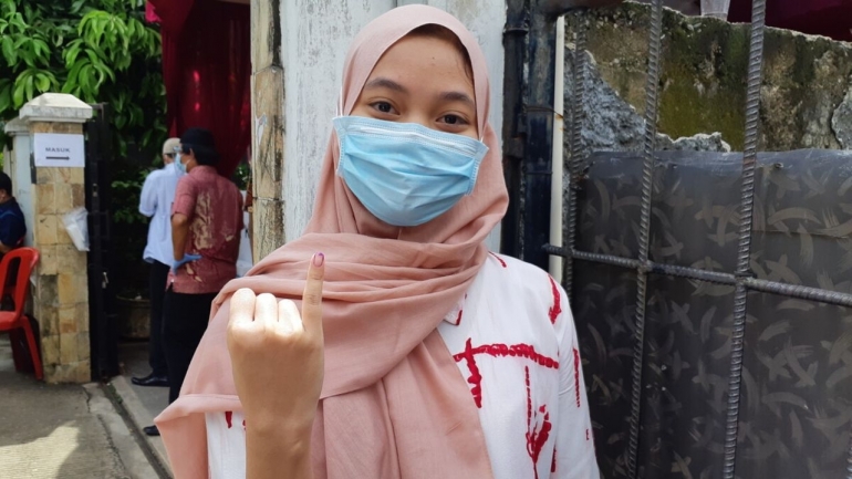 Syifa (20) menggunakan hak pilihnya pada Pilkada Kota Depok, Rabu (9/12/2020)  | KOMPAS/AGUIDO ADRI