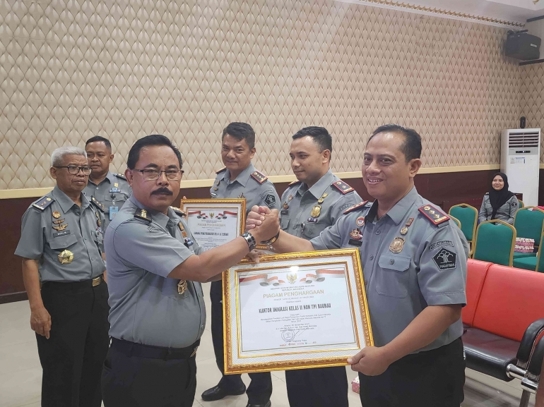 Kepala Kantor Imigrasi Baubau (kanan) menerima penghargaan yang penyerahan nya diwakilkan Oleh Kepala Bidang Hak Asasi Manusia (kiri)