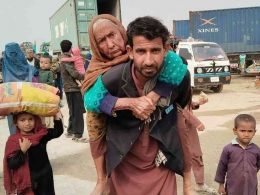 Seorang pengungsi Afghanistan di Pakistan menggendong ibunya saat pulang ke Pakistan. | Sumber: Islam Gul Afridi/Al Jazeera
