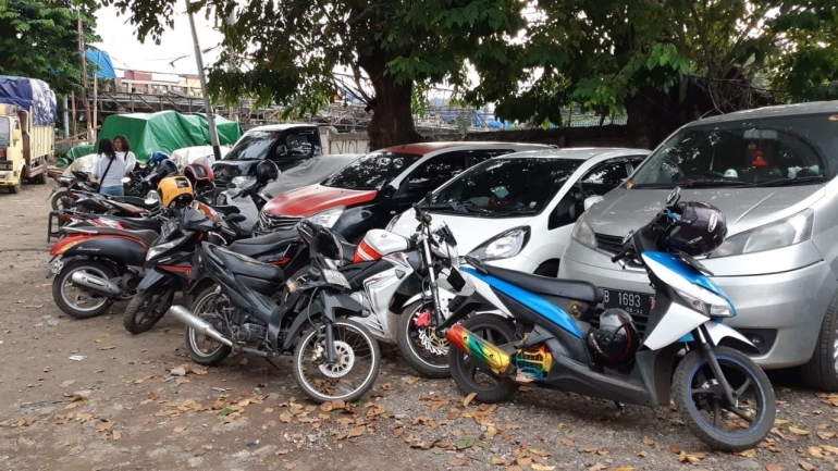 Sepeda motor dan mobil pengunjung pasar diparkirkan di sebidang tanah kosong | YOLA SASTRA UNTUK KOMPAS 