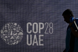 ilustrasi: Seorang pekerja berjalan melewati logo COP28 menjelang KTT iklim PBB tersebut di Dubai, Uni Emirat Arab (UEA), Selasa (28/11/2023). (Foto: AFP/JEWEL SAMAD via kompas.com) 