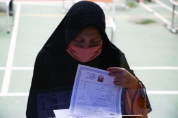 Orangtua siswa memeriksa dokumen anaknya saat melapor di posko penerimaan peserta didik baru (PPDB) SMK Negeri 15, Jakarta Selatan, Selasa (23/6/2020).(KOMPAS/PRIYOMBODO)