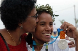 Lisa Rumbewas mendapat ciuman dari ibunya seusai meraih medali perak Olimpiade Athena 2004 nomor angkat besi di kelas 53 kilogram. Foto: KOMPAS/ARBAIN RAMBEY