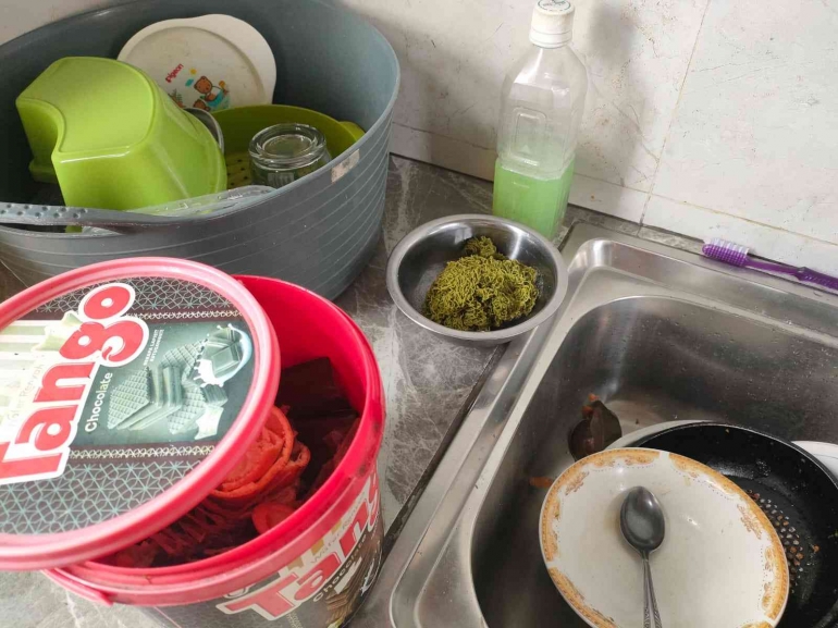 Wadah tertutup untuk mengumpulkan sampah organik sisa makanan di rumah, menggunakan toples bekas makanan pabrikan.