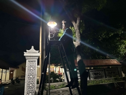 Pemasangan Fitting Lampu Hemat Energi Berbasis Sensor Cahaya di Depan Balai Desa Sidorejo (Dokumen Pribadi)